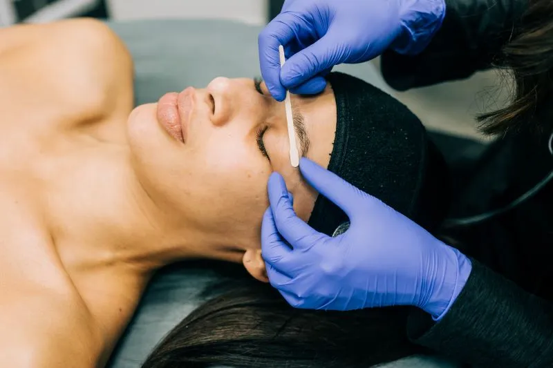 Woman receiving brow waxing treatment